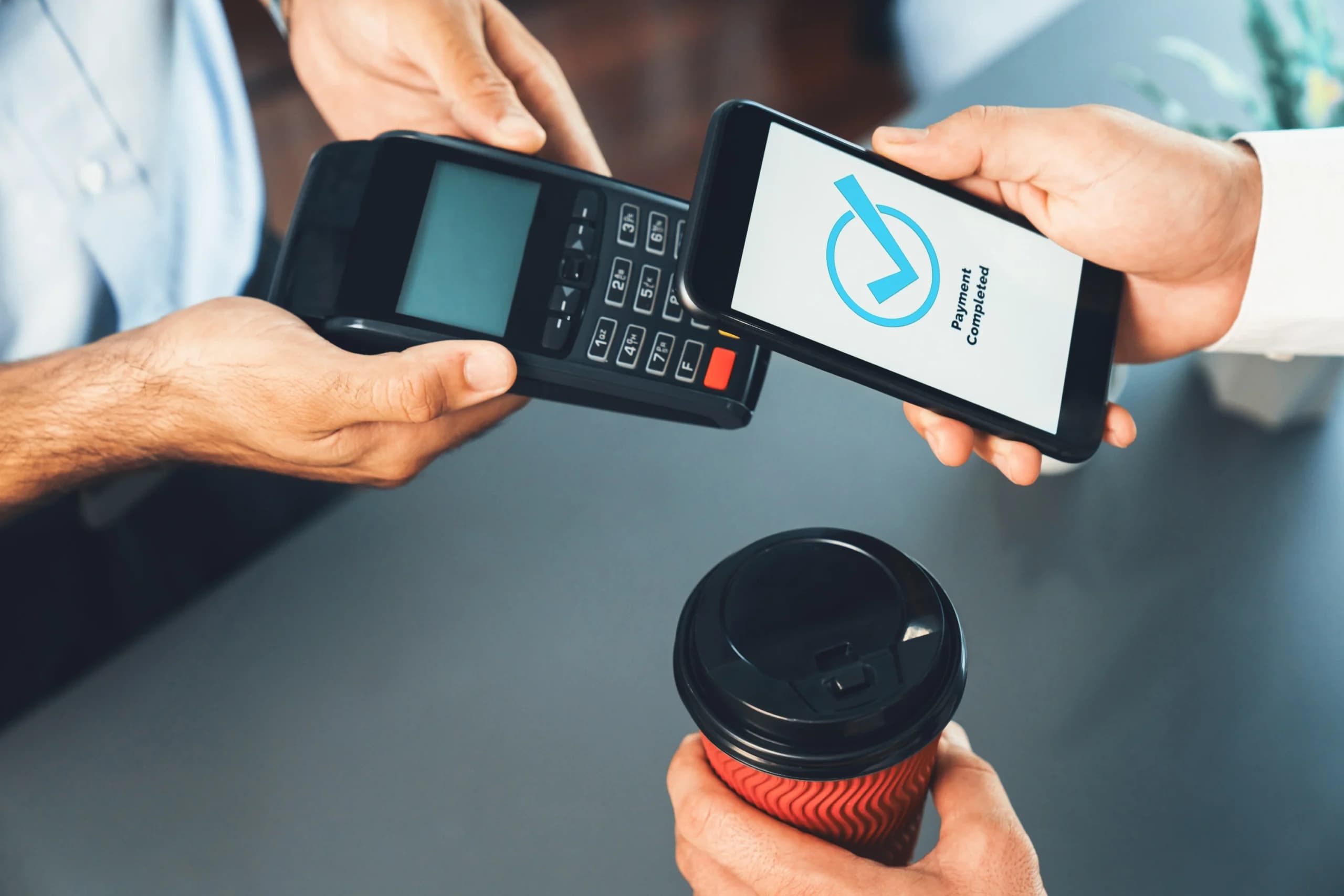 person-holding-phone-cup-coffee-with-phone-that-says-mobile-payment-it